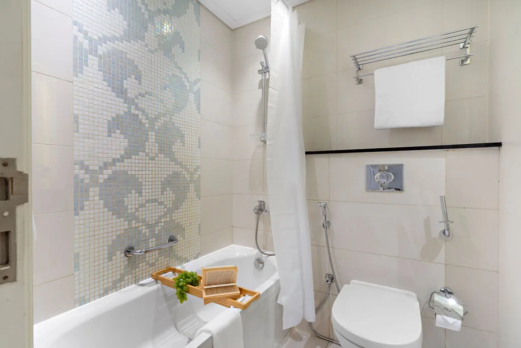 A tiled bathroom with a bathtub, shower curtain, and toilet.