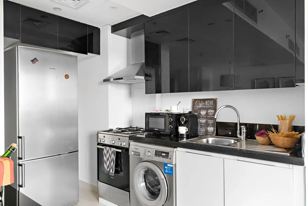 A modern kitchen with a refrigerator, countertop appliances, and a sink.