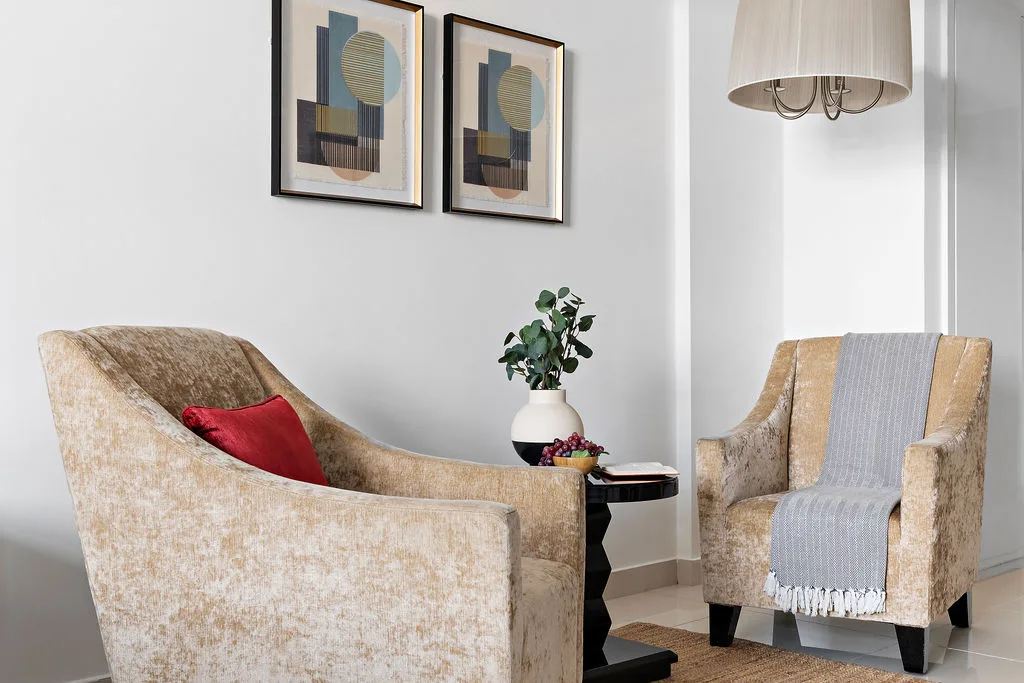 A sitting area with upholstered seating, framed artwork, and a small table.