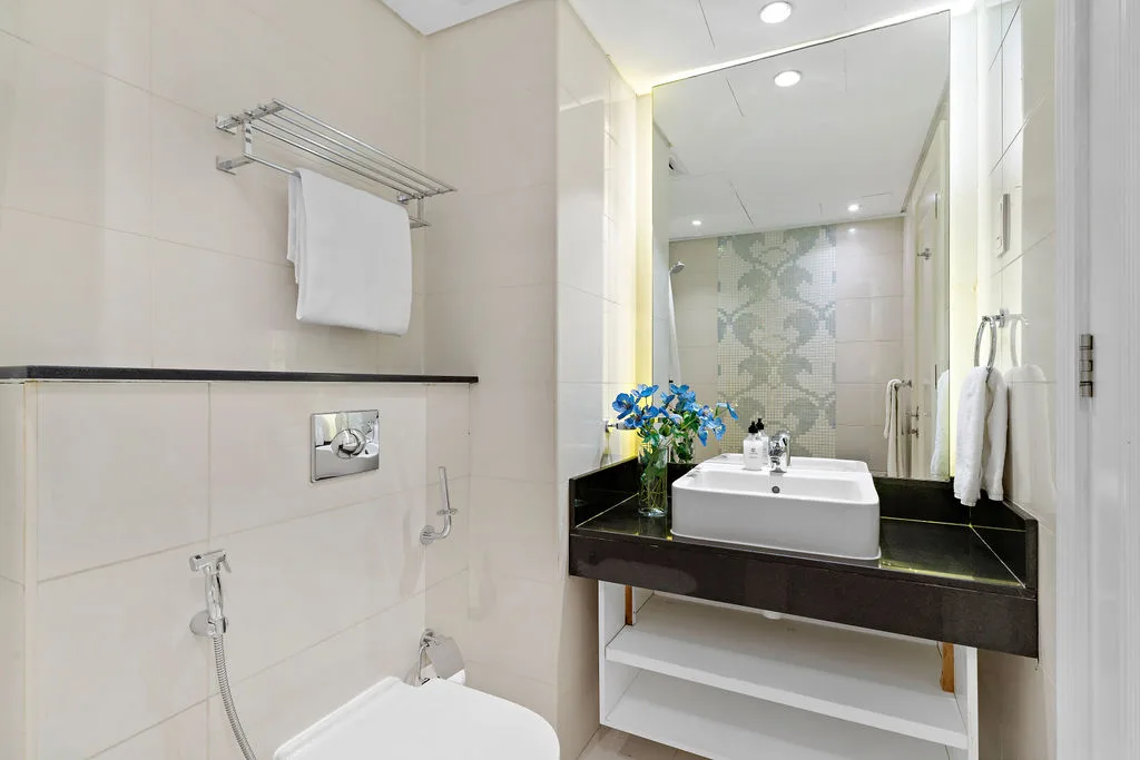 A tiled bathroom with a sink, mirror, and toilet.