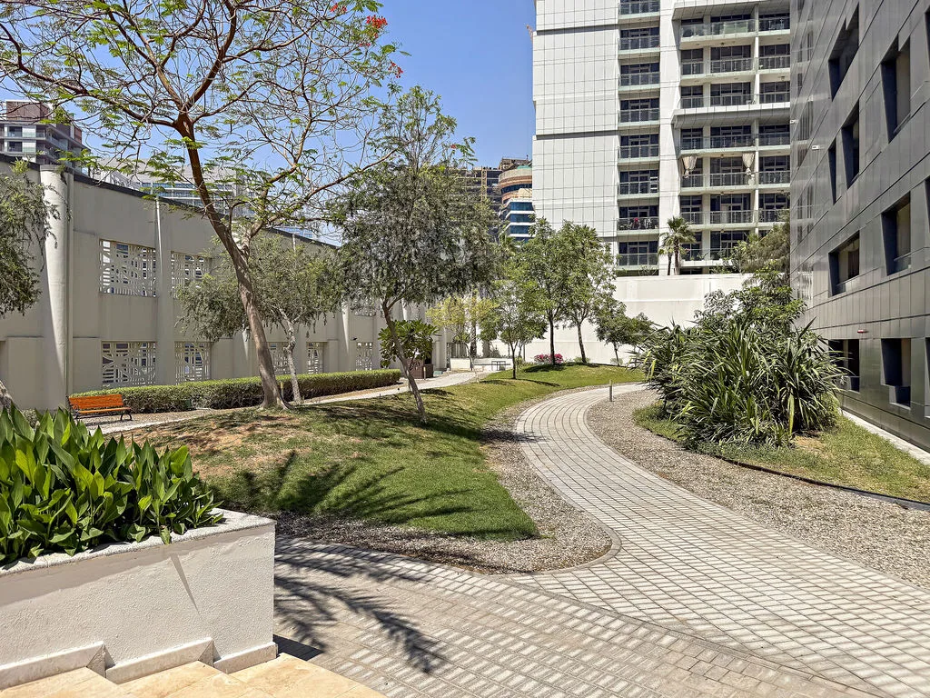 A landscaped courtyard with a curving paved walkway between modern buildings.
