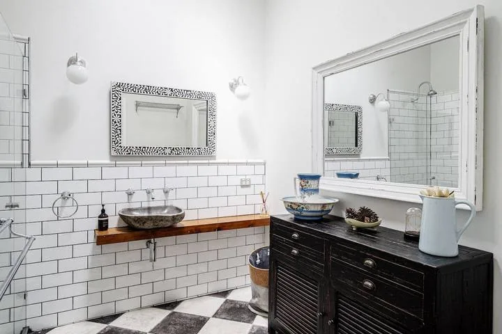 A tiled bathroom with a wall-mounted sink and a dark vanity beneath a large mirror.