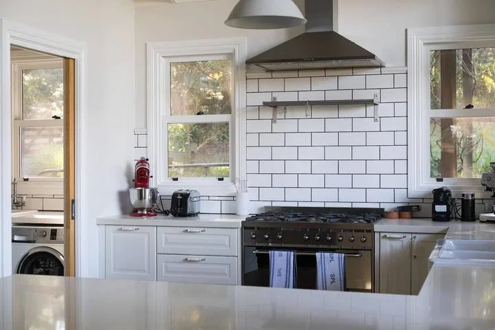 A bright kitchen with a large stove beneath a tiled backsplash.