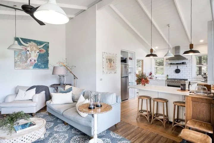 An open-plan living room and kitchen with light-colored seating and a central island.