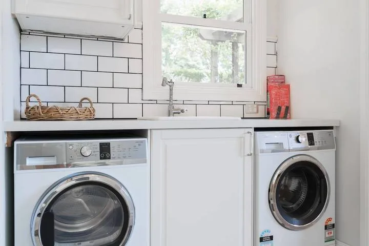 A laundry area with two front-loading washing machines beneath a window.