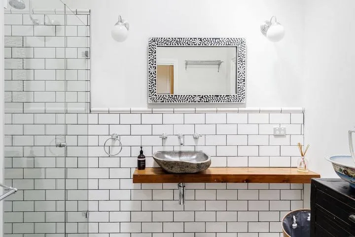 A bathroom vanity with a vessel sink, wall mirror, and tiled backsplash.