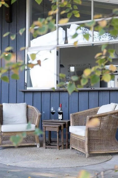 An outdoor seating area beside a blue wall, with wicker chairs and a small table.