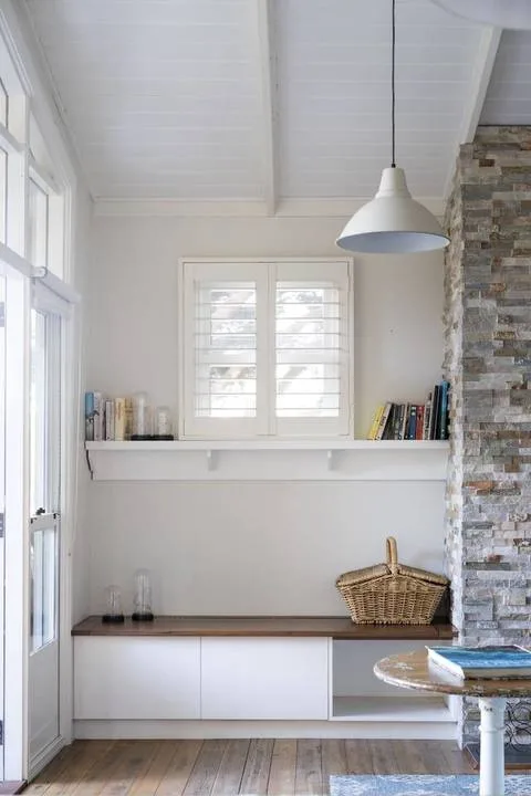 A bright room with a long built-in bench, books, and a pendant light.