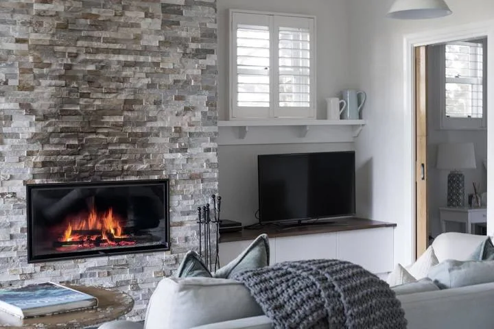 Living room with a stone fireplace and television beside the seating area.