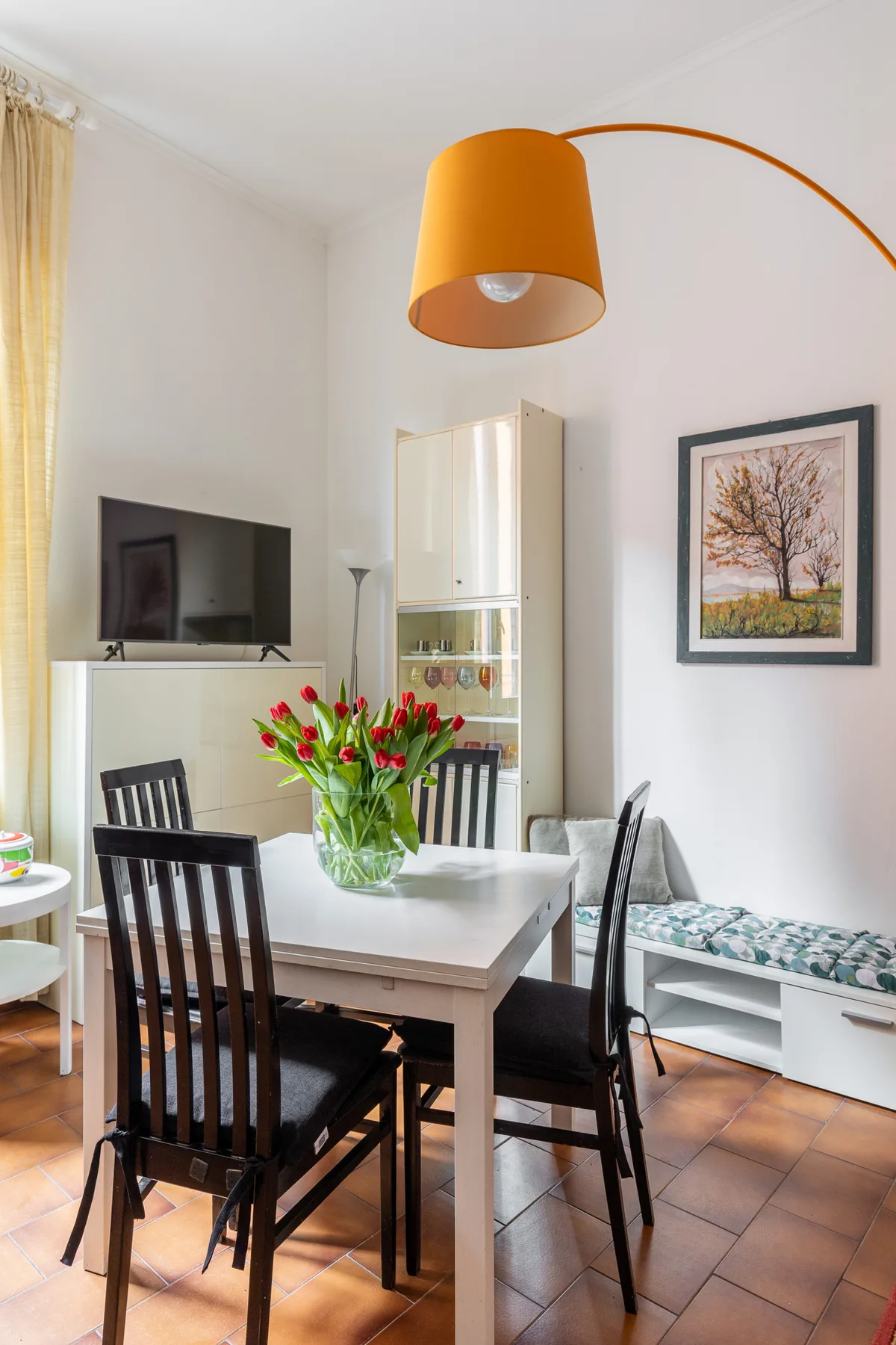 A dining area with a table, chairs, and a vase of flowers.