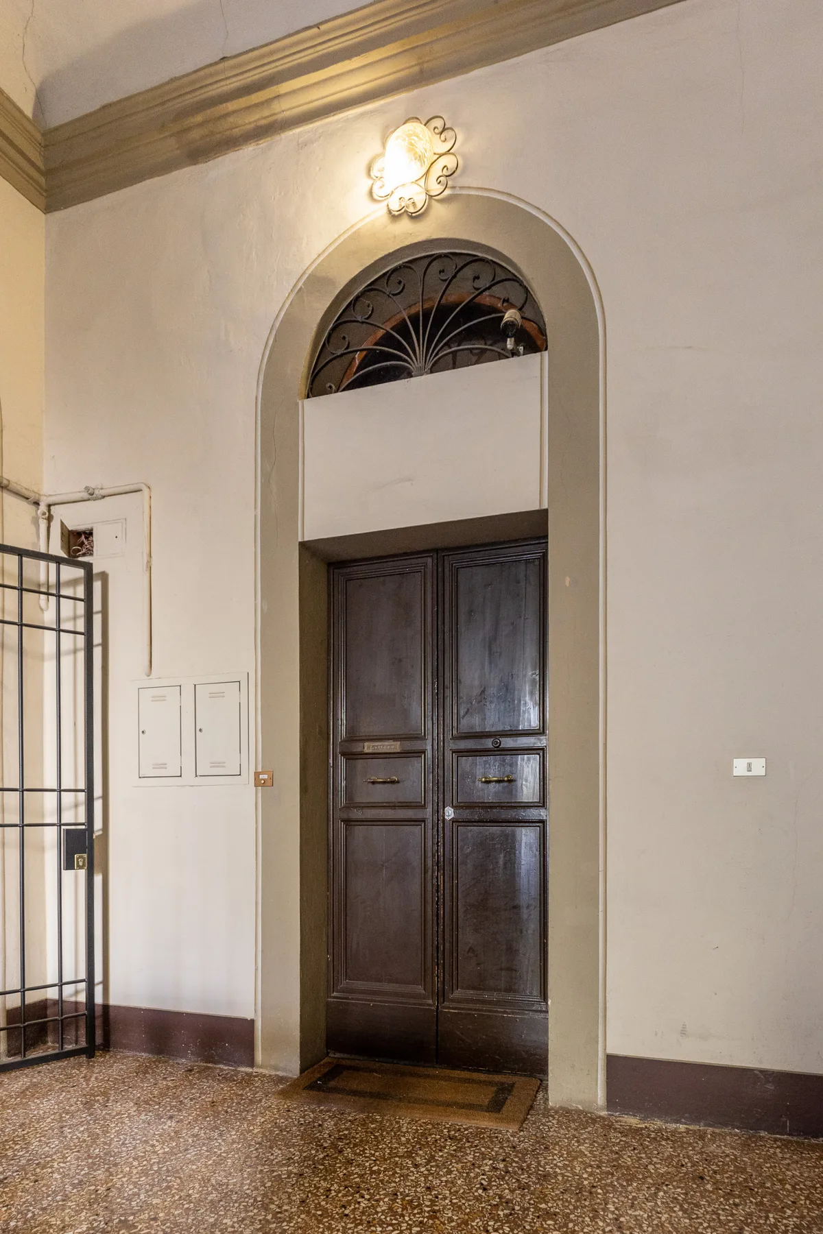 An arched dark wooden door stands beneath a decorative fanlight.