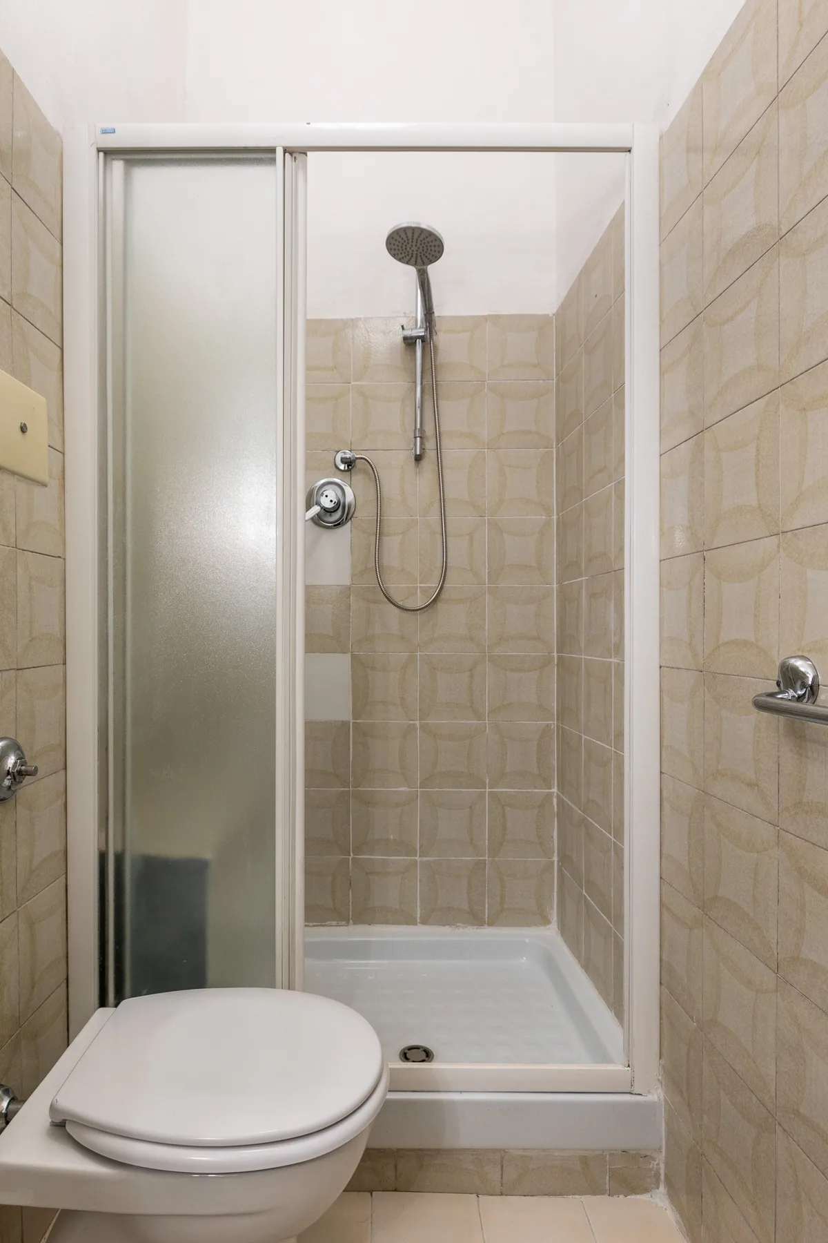 A tiled bathroom with a shower and toilet.