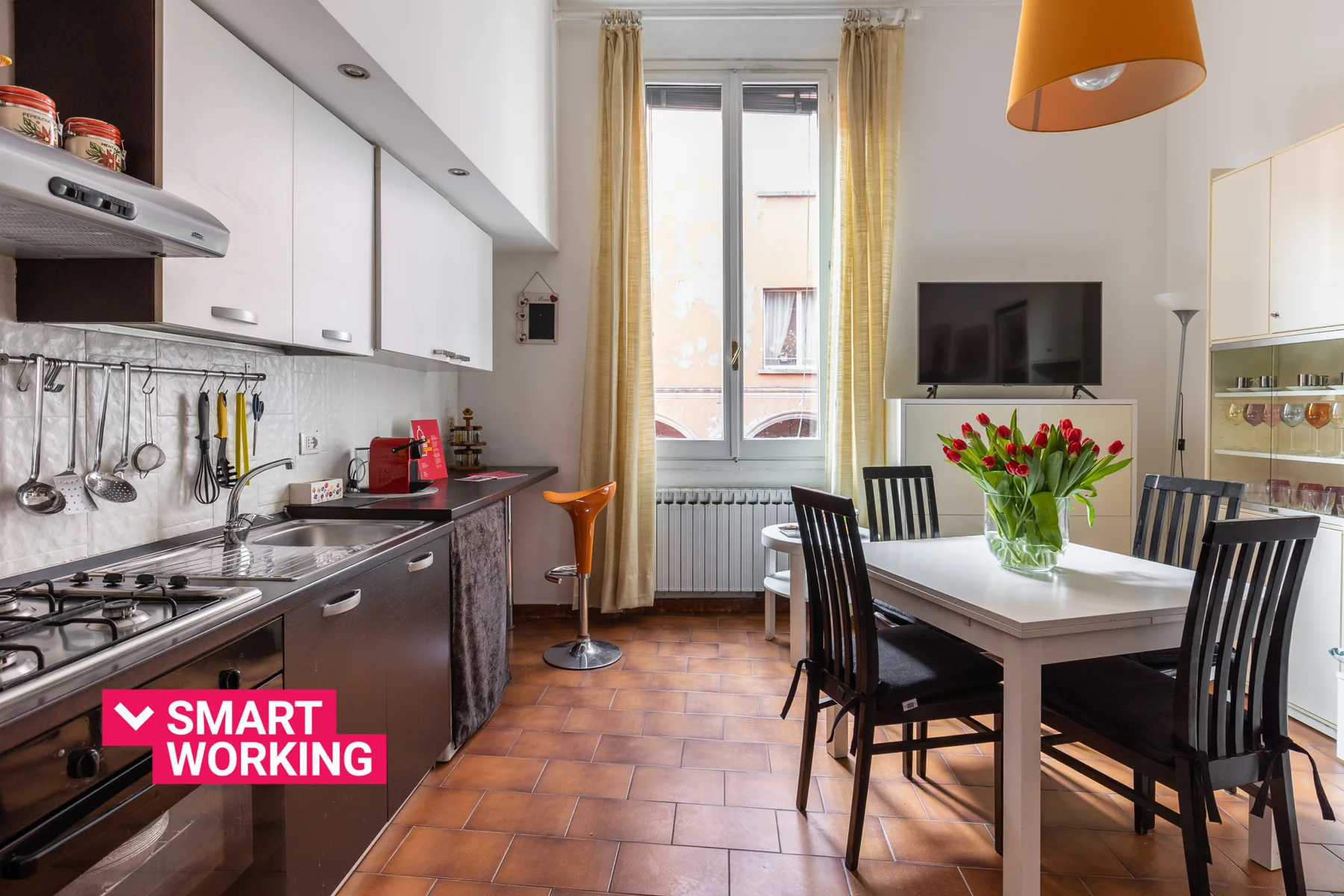 A kitchen and dining area with a table, chairs, and flowers.