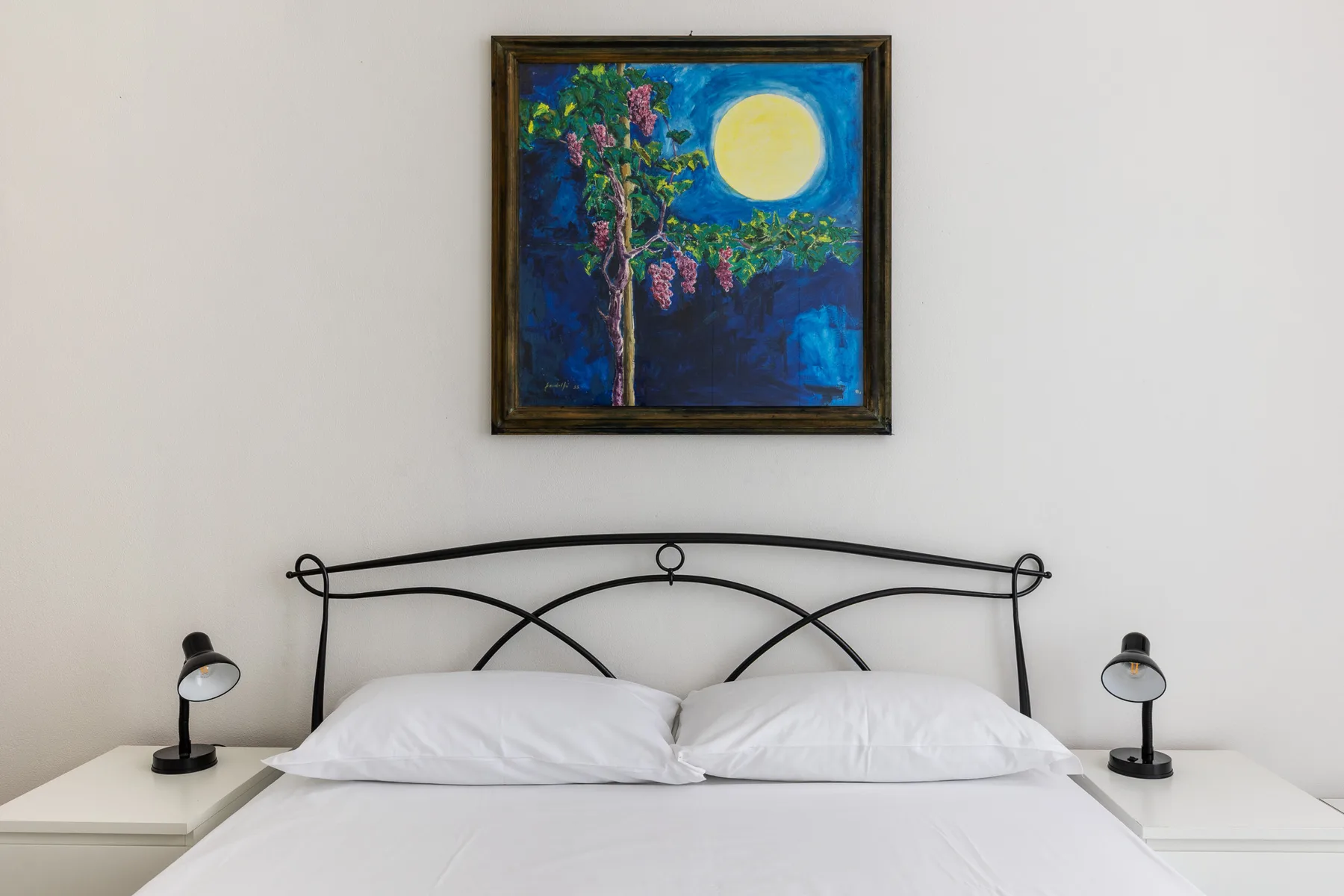 A bedroom with a neatly made bed and colorful artwork above the headboard.