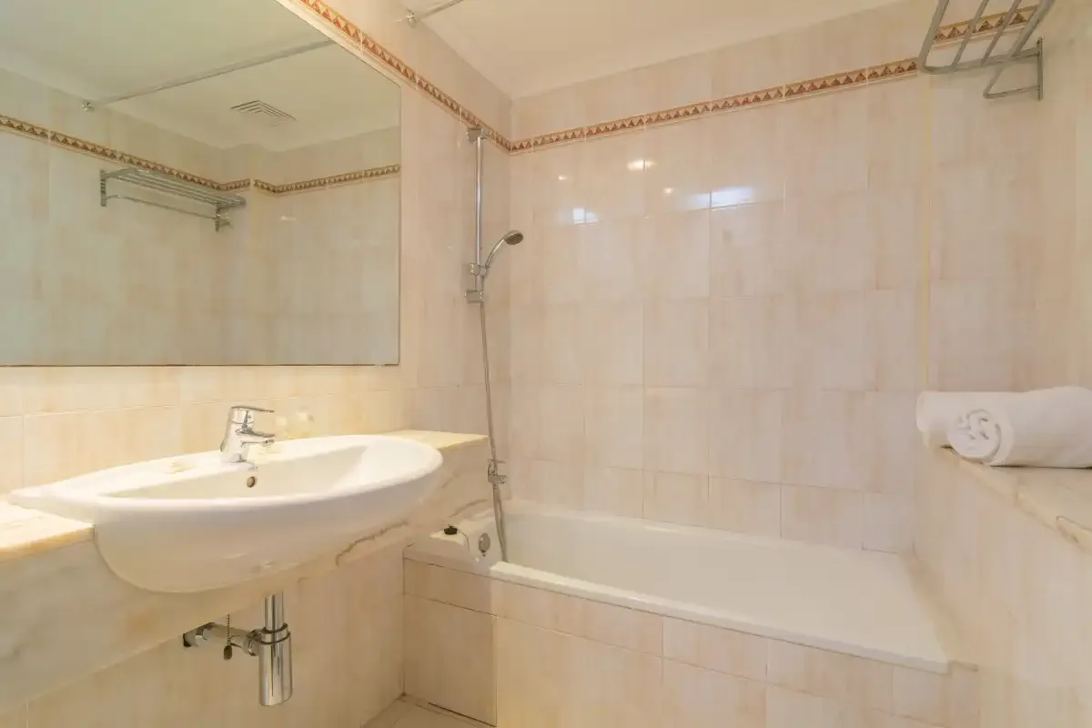 Un baño alicatado con lavabo, espejo y bañera.