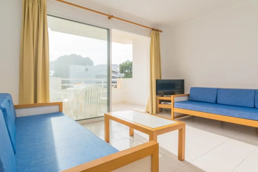 A bright living room with blue seating, a coffee table, and sliding glass doors.