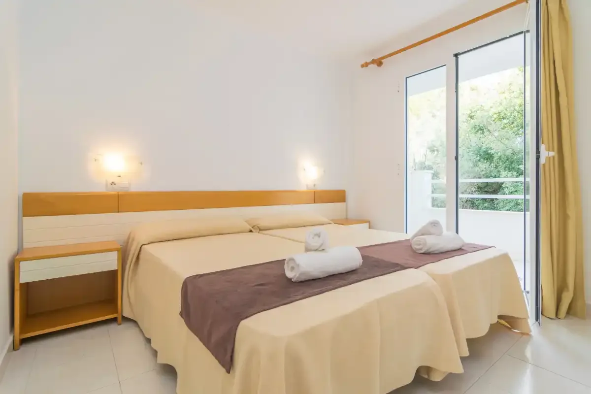 Un dormitorio luminoso con una cama amplia y una puerta de vidrio que da a la vegetación.