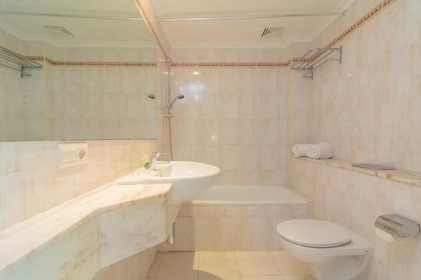 Un baño alicatado con bañera, ducha y lavabo.