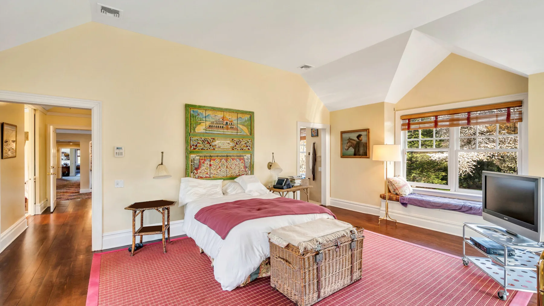 Un dormitorio con una cama, una ventana grande y un televisor.