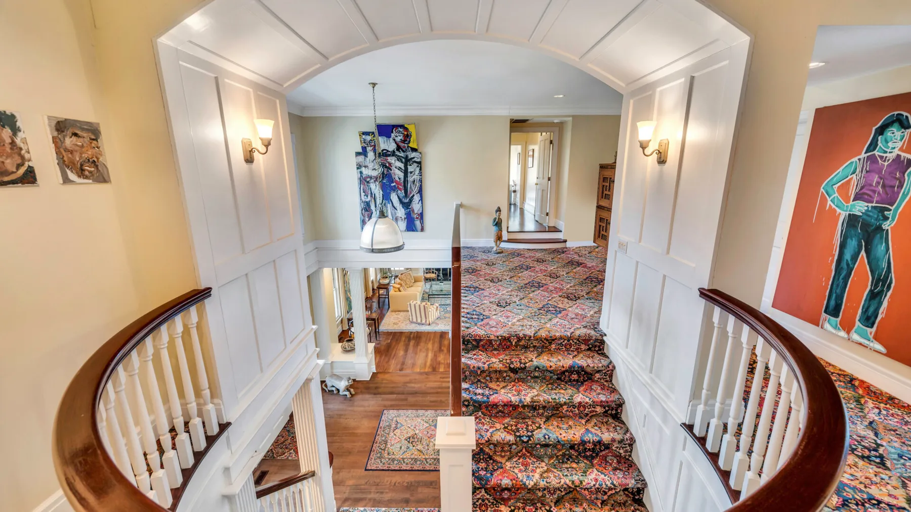 Una escalera interior ornamentada con alfombra estampada y barandales blancos curvos.