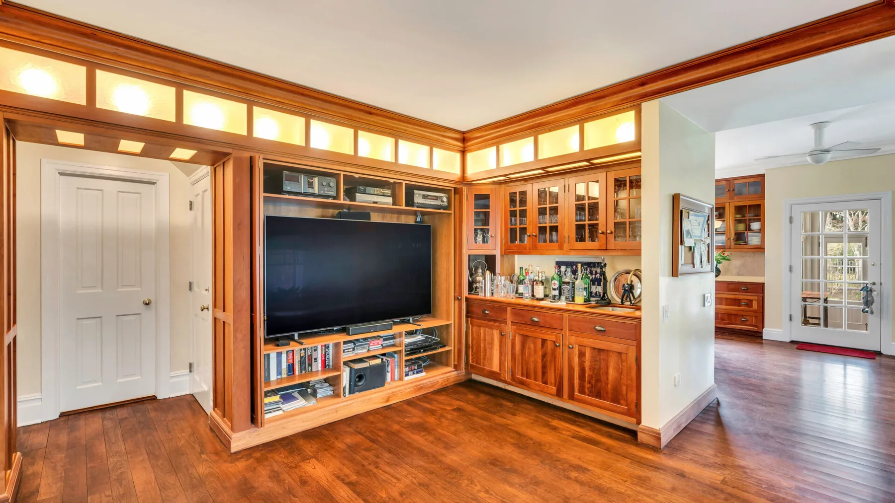 Una sala de estar con paneles de madera, estanterías empotradas y un televisor grande.