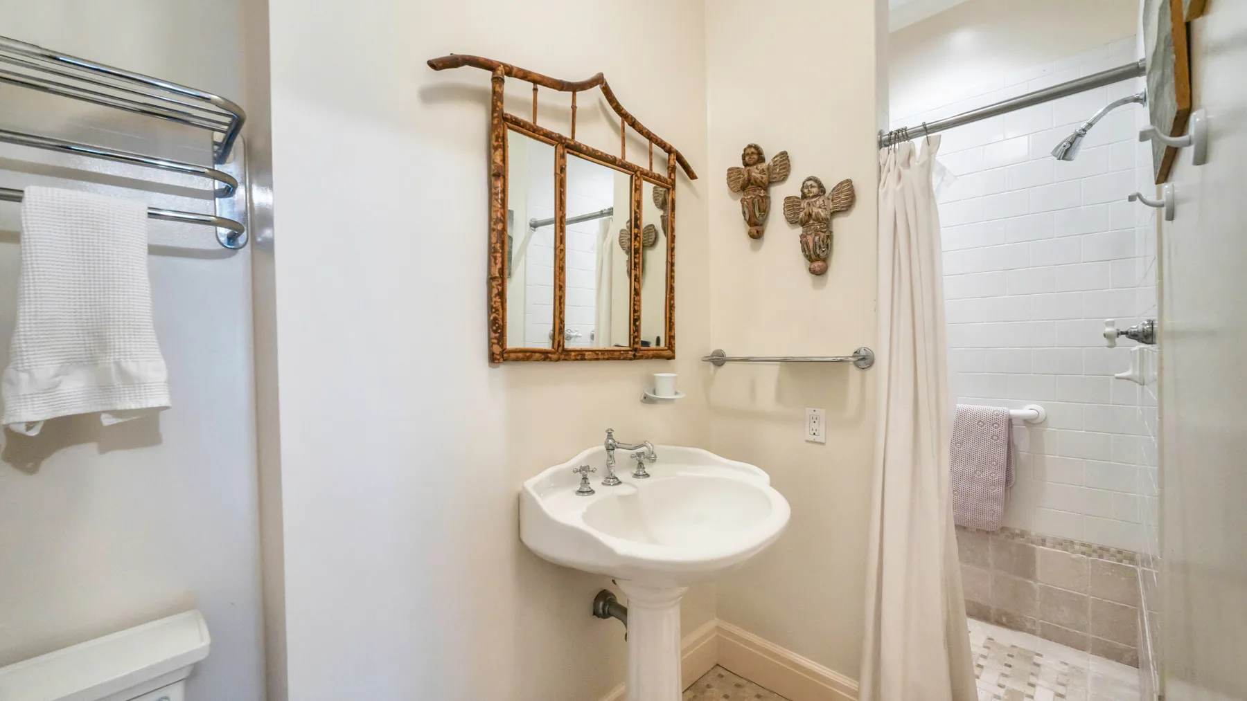Un baño con un lavabo de pedestal y una ducha detrás de una cortina.