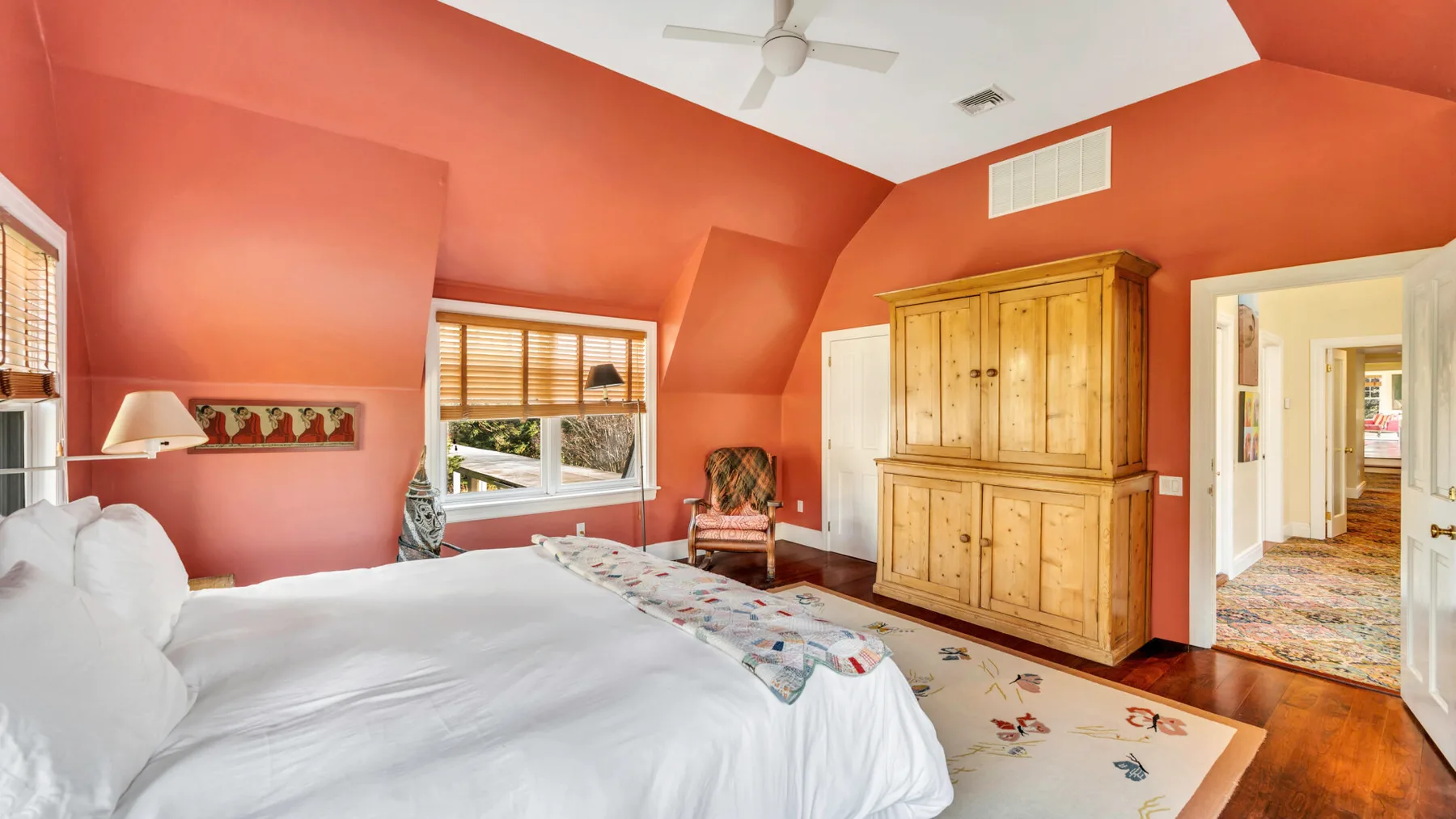 Un dormitorio con una cama grande, un armario de madera y ventanas con persianas.