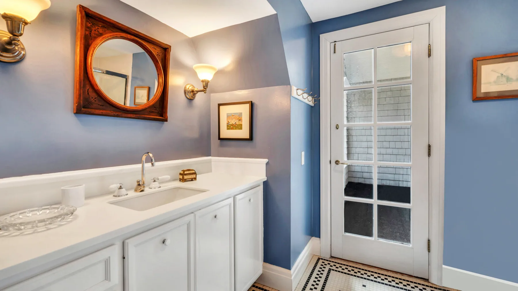 Un tocador de baño con lavabo está junto a una puerta con paneles de vidrio.