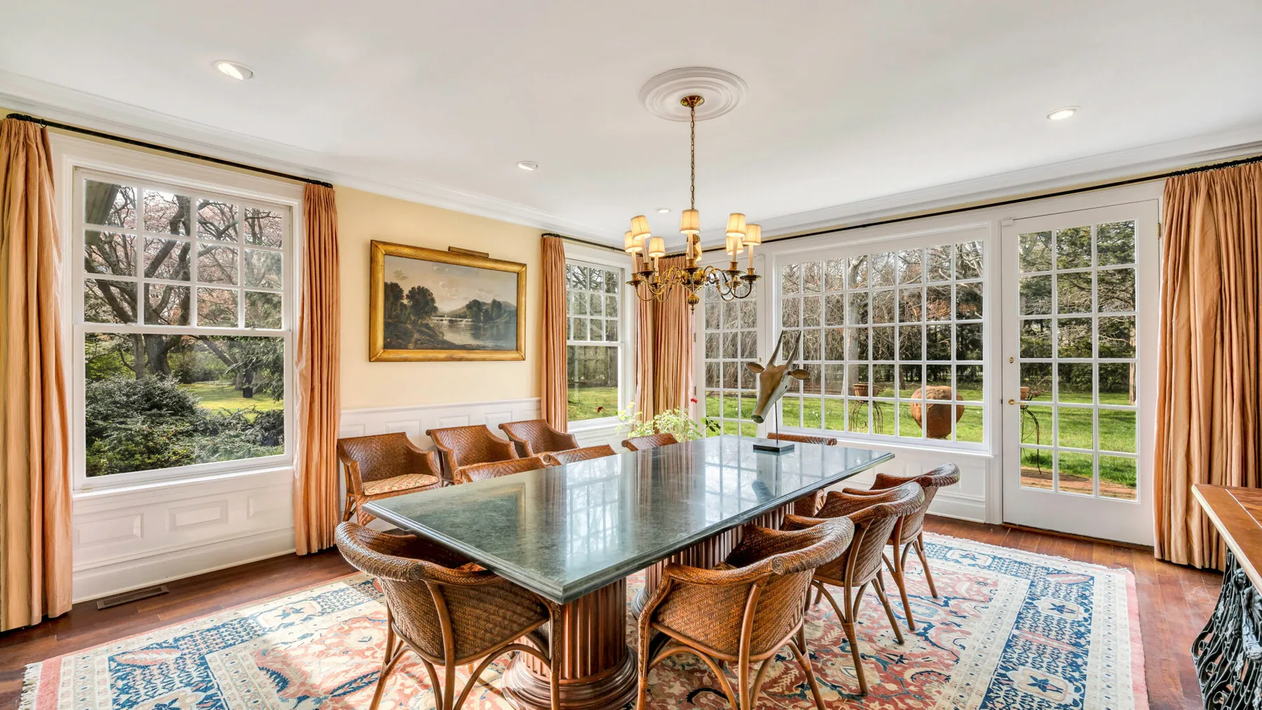 Un comedor luminoso con una mesa grande y ventanas con vistas al jardín.