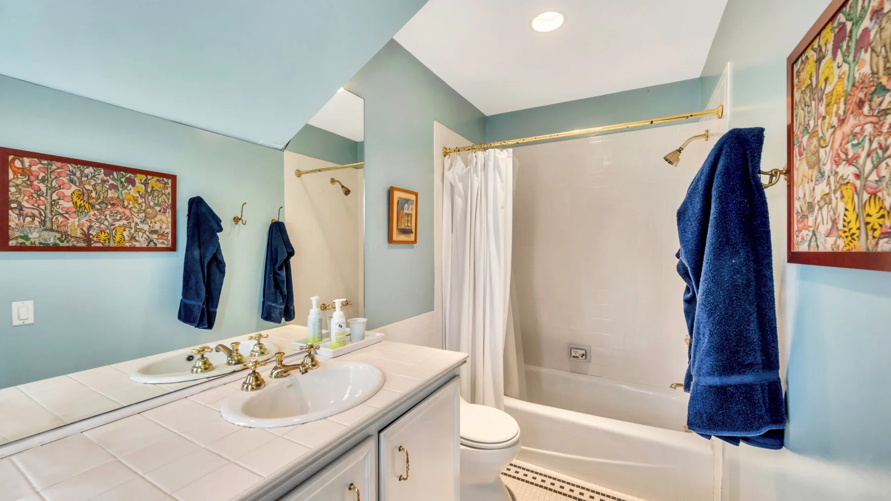 Un baño con un tocador largo, lavabo y bañera detrás de una cortina de ducha.