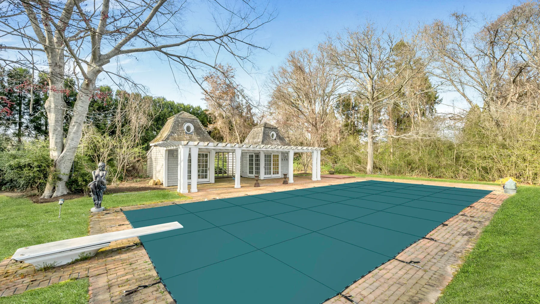 Una piscina cubierta está en un jardín rodeado de árboles.
