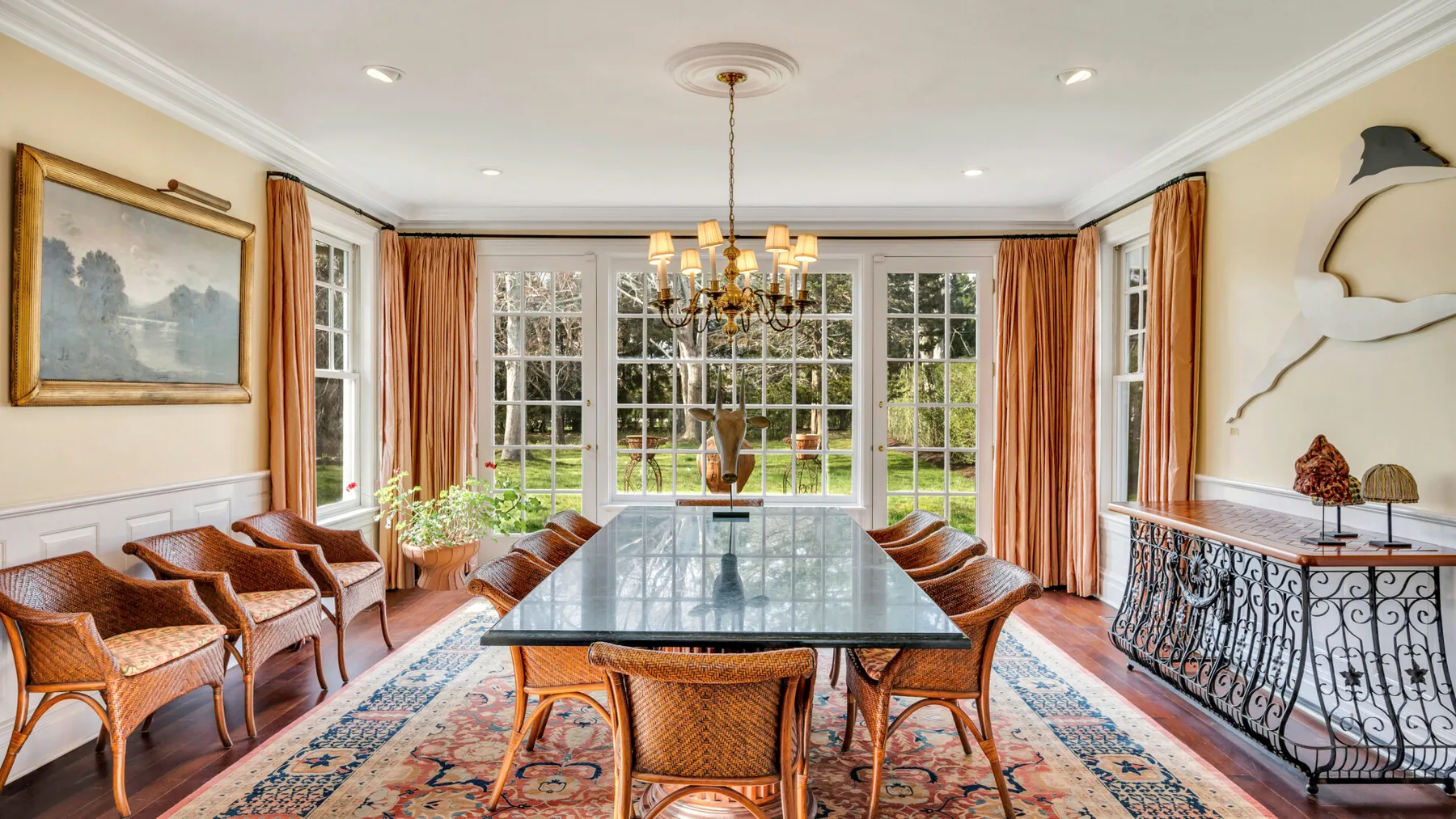 Un comedor luminoso tiene una mesa larga junto a grandes ventanas.