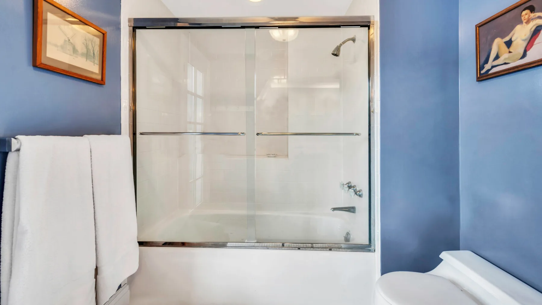 Un baño con una ducha de vidrio y paredes azules.