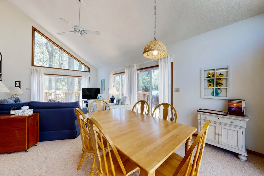 Una luminosa sala de estar y comedor con una mesa de madera y asientos azules.