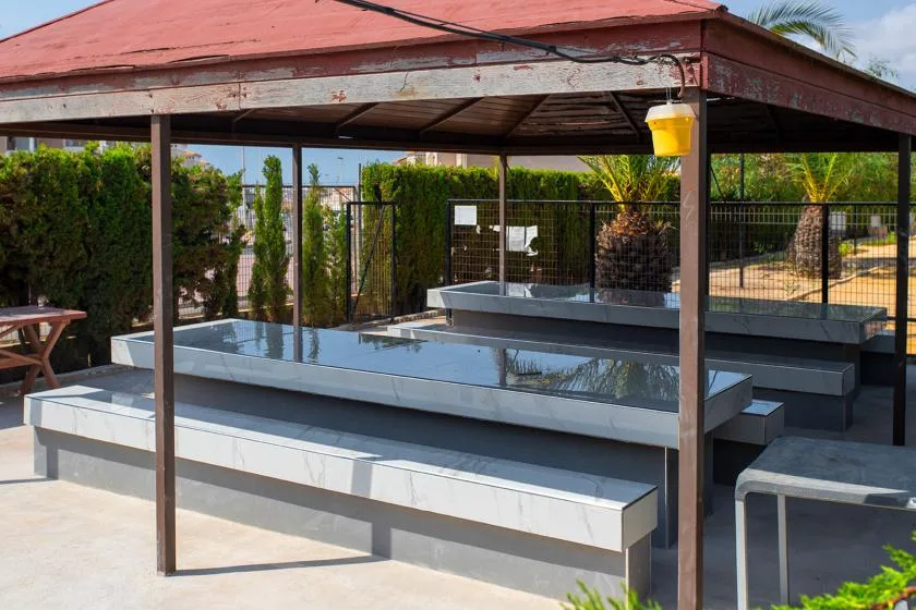 A covered outdoor seating area with long built-in benches and a table.