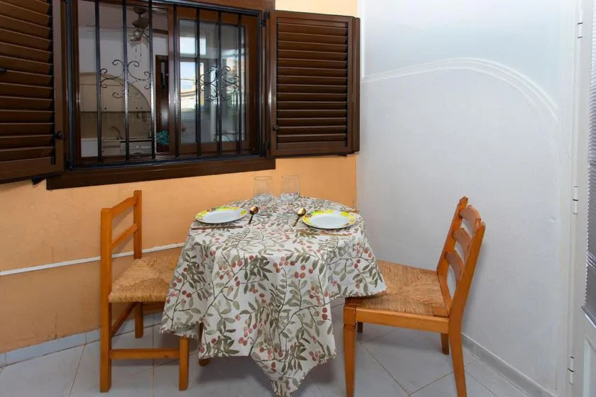 A dining area with a round table set with plates and wooden seating.