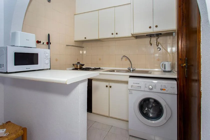 A compact kitchen with white cabinets, a countertop, and a washing machine.
