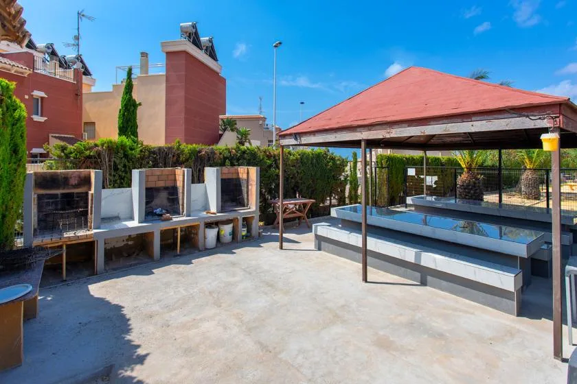 An outdoor patio with a red-roofed shelter and built-in seating.