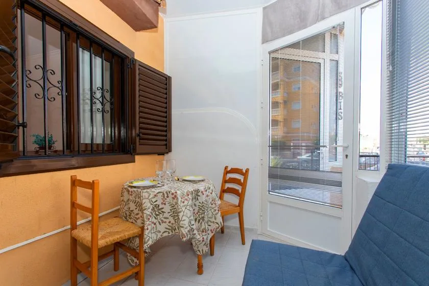 A small dining area with a patterned tablecloth beside a large window.