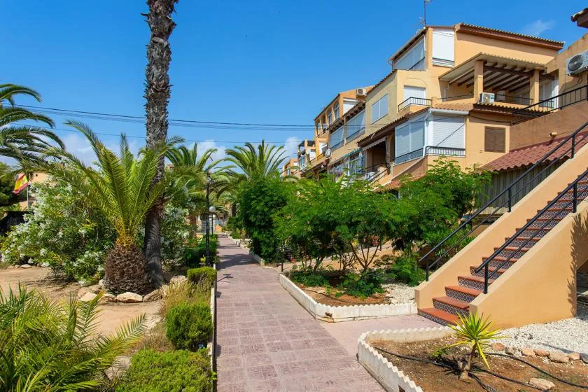 A paved walkway runs through landscaped grounds beside apartment buildings and an outdoor staircase.