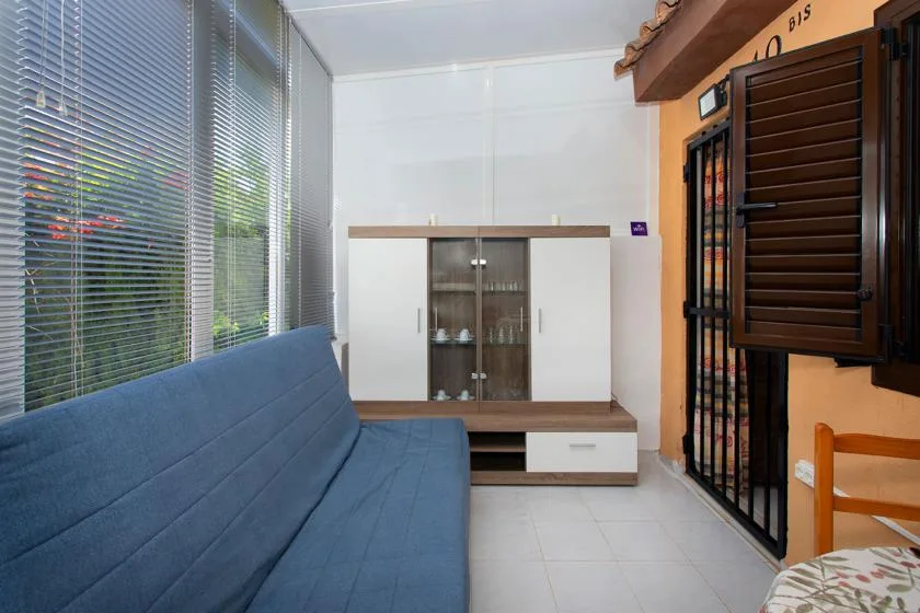 A sitting area with blue seating, a glass-front cabinet, and large windows.