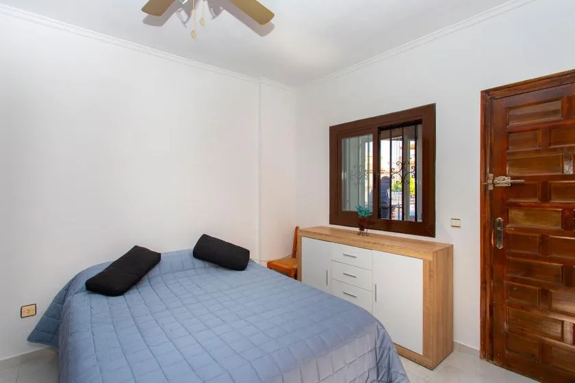 A bedroom with a bed beside a window and a wooden door.