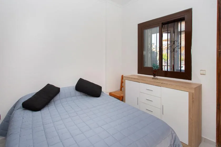 A bedroom with a bed beside a window and a dresser.