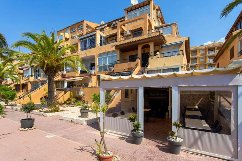A multi-story building with balconies stands beside a paved outdoor patio.