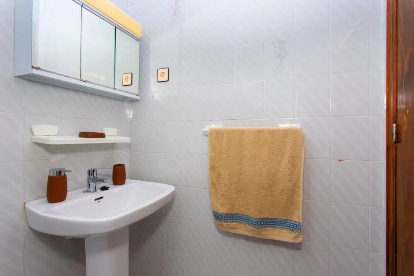 A bathroom with a sink, wall mirror, and towel hanging on the wall.