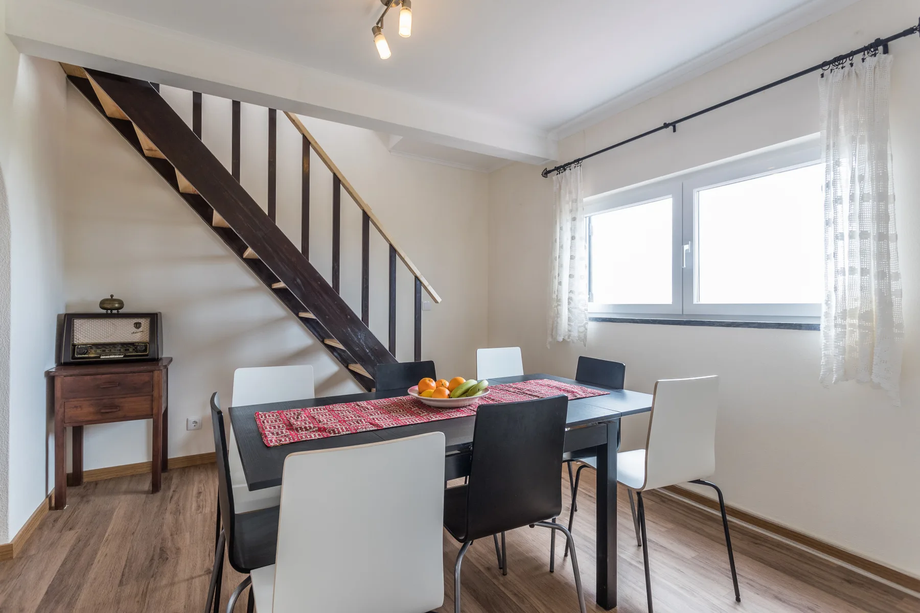 A dining area with a table and chairs beneath a staircase.