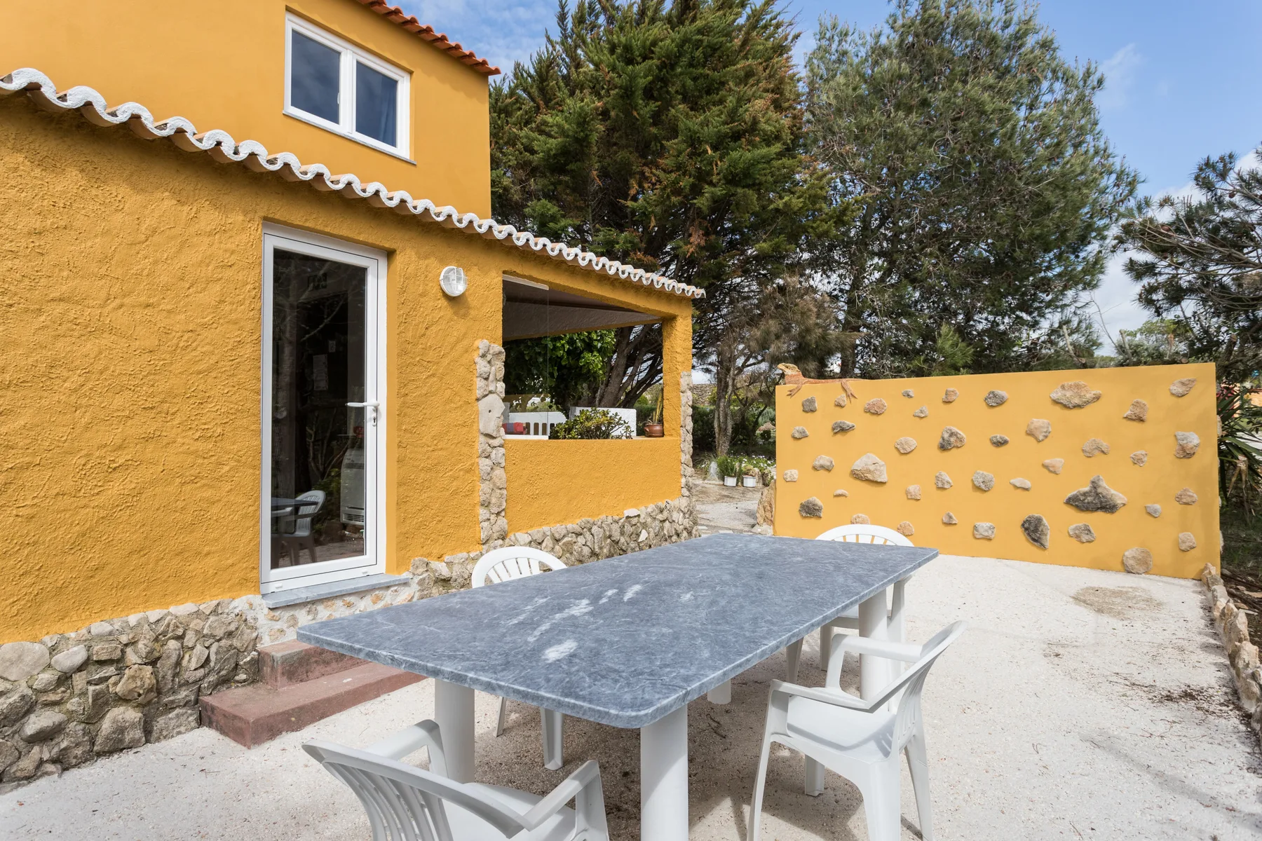 A yellow house opens onto a patio with a table and seating.