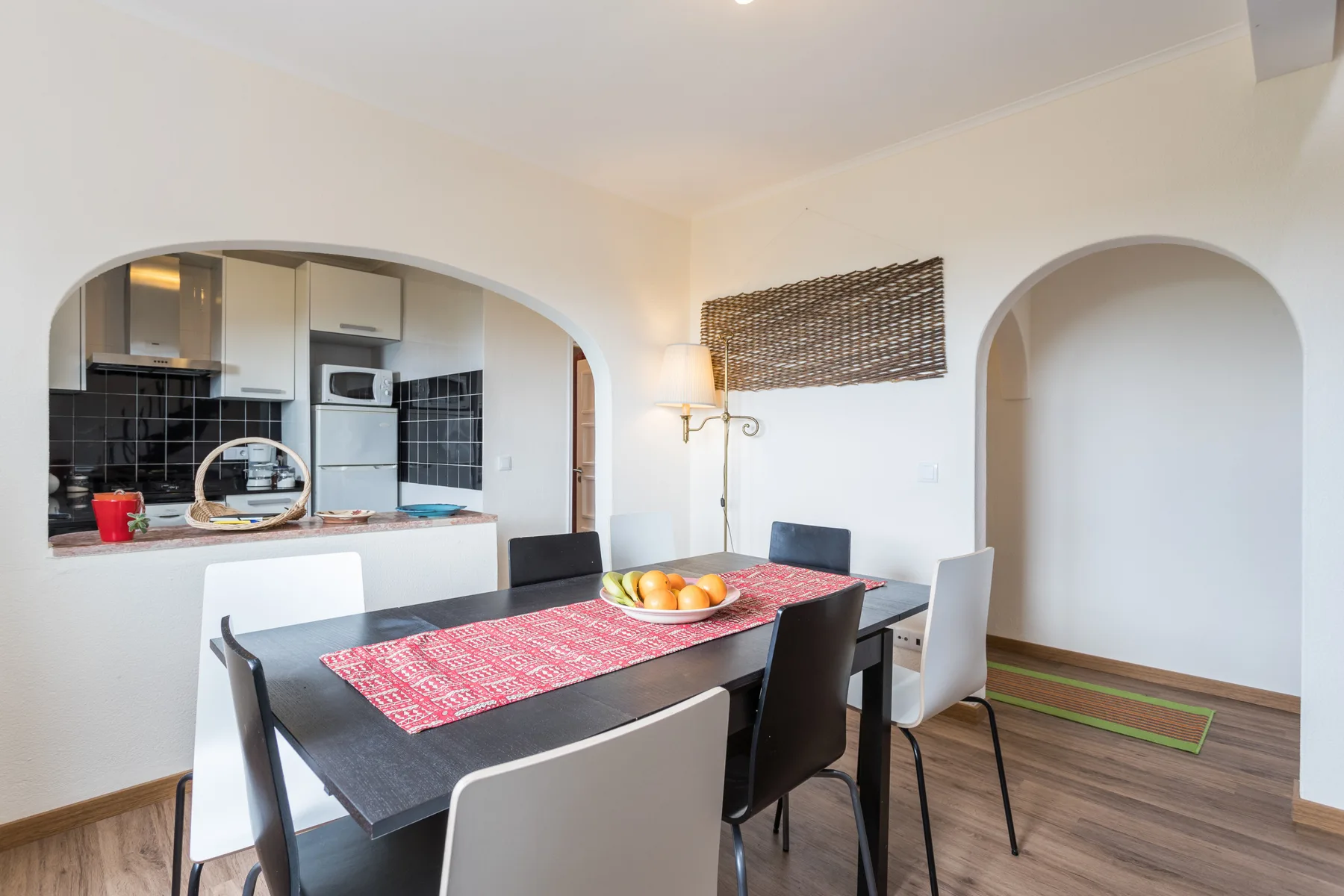 A dining area with a table set beside an arched opening to the kitchen.