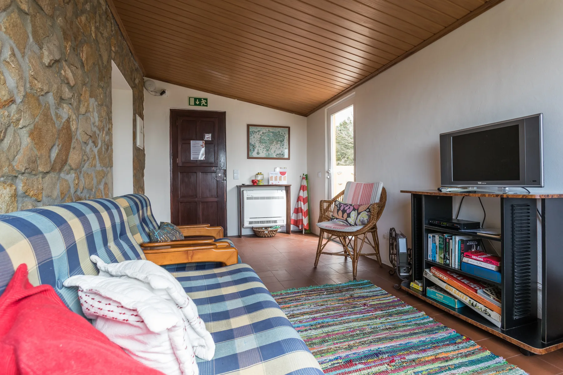 A living room with patterned seating, a television, and a colorful rug.