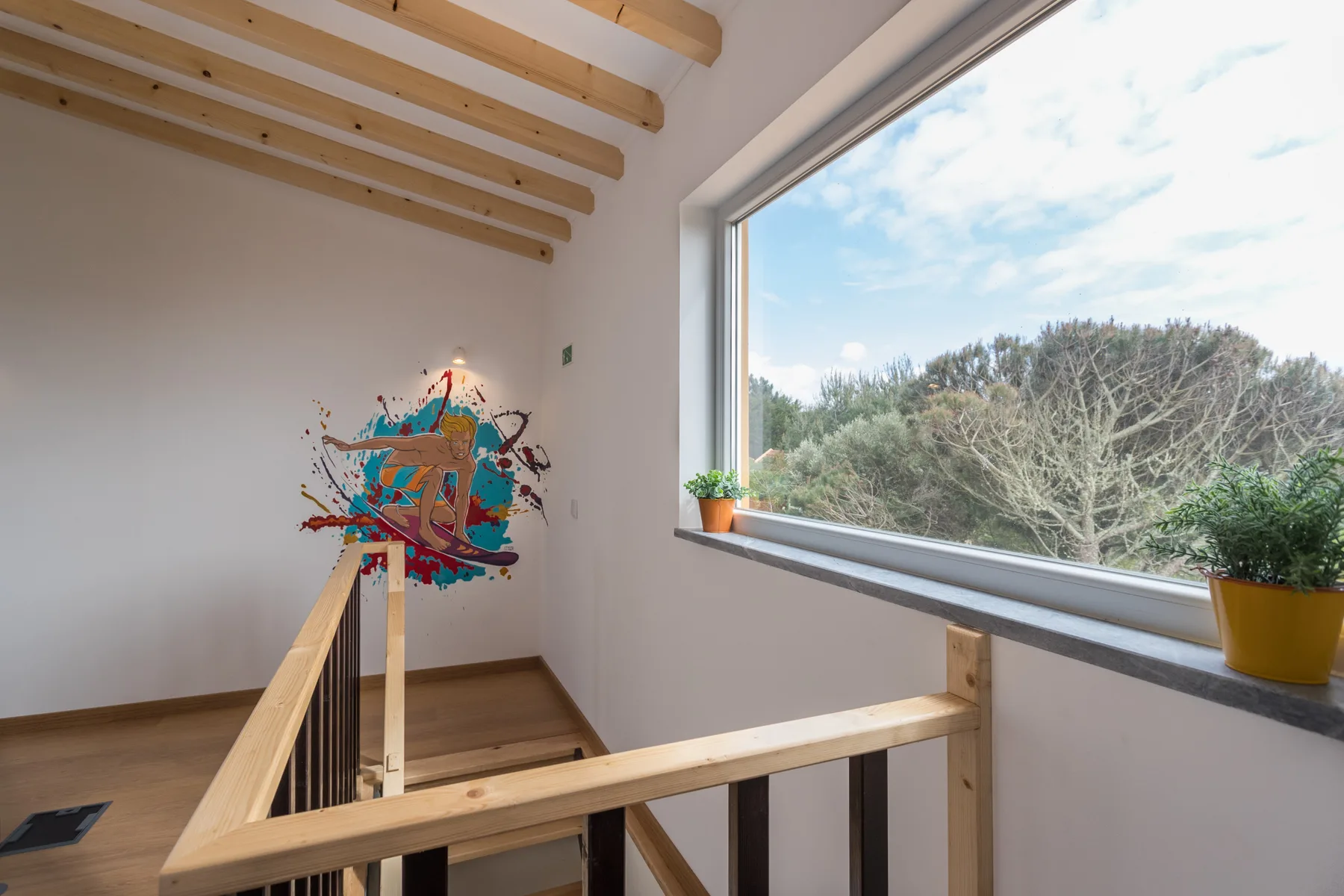 An interior landing overlooks a wooded view through a large window.